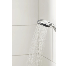 Douchette à main avec eau courante devant des carreaux muraux