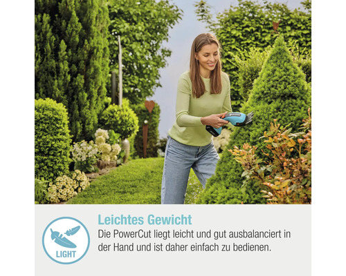 Une femme coupe un arbuste dans le jardin avec des cisailles à gazon sans fil.