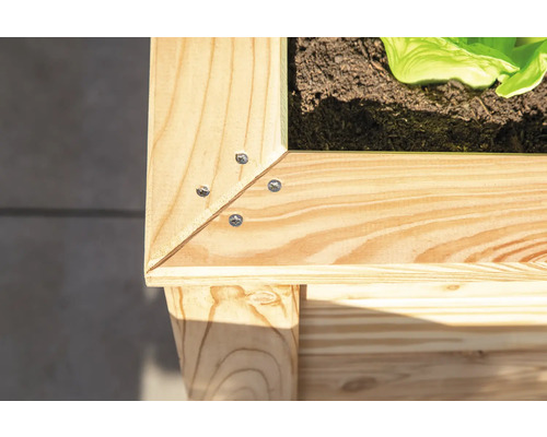 Vue détaillée d''un potager surélevé en bois avec des vis dans les coins.