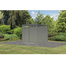 Gartenschrank aus Metall mit Doppeltür und Oberlicht auf gepflastertem Untergrund vor Bäumen und Sträuchern.
