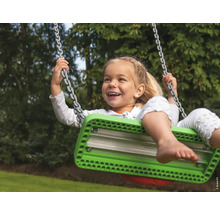 Fillette souriante se balançant sur une balançoire avec suspension à chaînes dans le jardin.