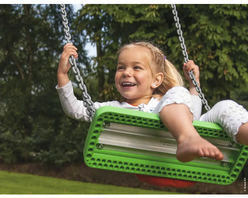 Enfant souriant sur une balançoire avec suspension à chaînes dans le jardin.