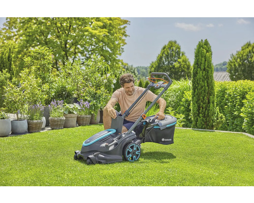 Ein Mann bereitet einen Rasenmäher für die Gartenarbeit vor, umgeben von einem gepflegten Garten