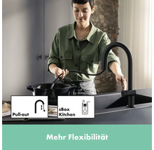 Frau benutzt eine schwarze Küchenarmatur mit Ausziehfunktion an einer Spüle.