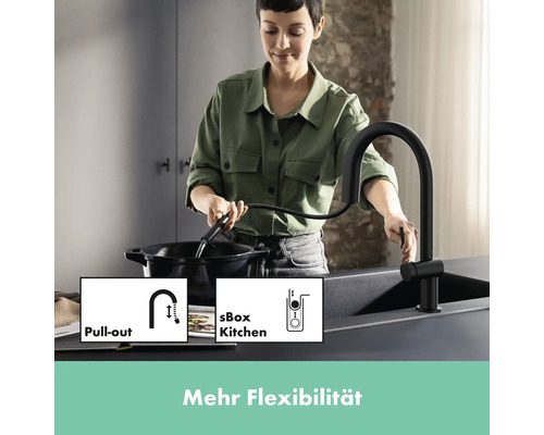Frau benutzt eine schwarze Küchenarmatur mit Ausziehfunktion an einer Spüle.