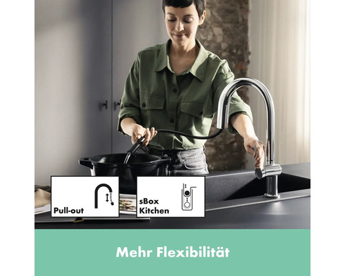 Frau benutzt Küchenarmatur mit Ausziehfunktion über einer Spüle
