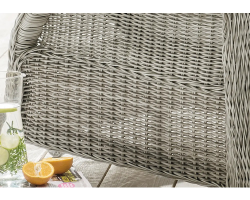 Detailaufnahme von einem grauen Korbsessel mit Getränkespender und angeschnittener Orange.