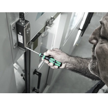 Ein Mann benutzt einen Schraubendreher, um eine Schraube an einem elektronischen Bauteil festzuziehen.