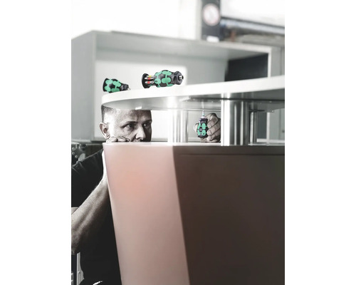 Un homme fixe un meuble avec un tournevis.