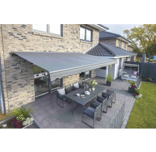 Terrasse mit Markise, Gartentisch und Stühlen vor Backsteinhaus