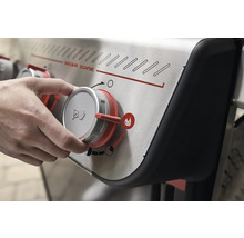 Gros plan d''un barbecue à gaz avec un bouton rotatif dans la main, qui règle la Sear Zone.