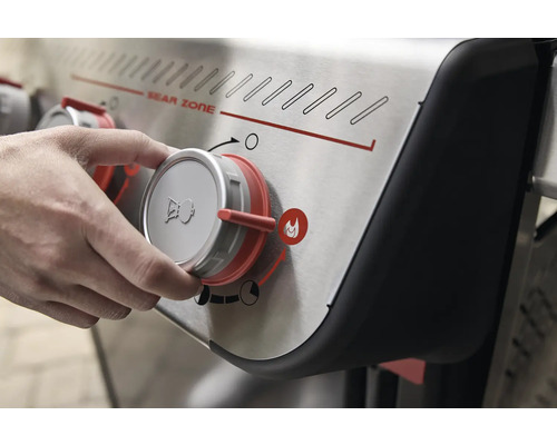 Gros plan d''un barbecue à gaz avec un bouton rotatif dans la main, qui règle la Sear Zone.