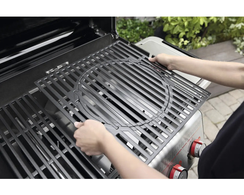 Une personne place une grille de barbecue dans un gril à gaz.