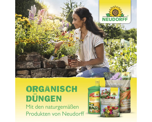 Eine Frau pflanzt Blumen in einem Garten, im Vordergrund Neudorff Dünger Produkte