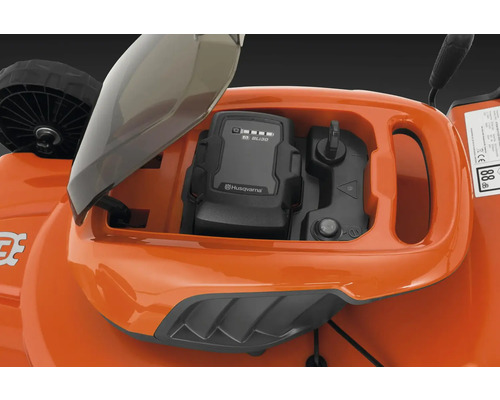 Gros plan du compartiment à batterie d''une tondeuse à gazon avec une batterie Husqvarna insérée