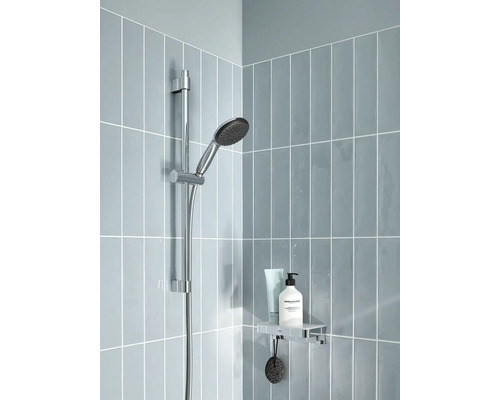 Duschstange mit Handbrause und Ablage in einer hell gefliesten Dusche.