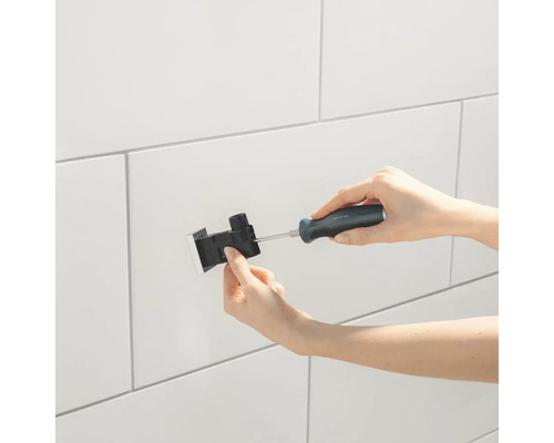 Installation eines Spülkastens mit Schraubendreher an einer gefliesten Wand.