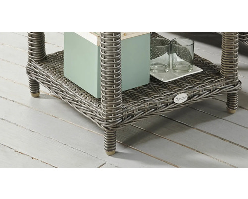 Detailansicht eines Rattantisches mit Ablagefläche, auf der sich ein Buch und Gläser befinden. Destiny Logo.