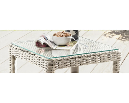 Gartentisch aus Rattan mit Glasplatte, darauf liegen eine Zeitschrift und eine Schale mit Snacks
