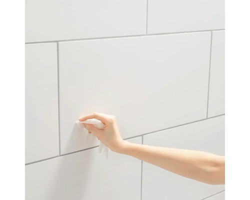 Reinigung einer gefliesten Wand mit einem Reinigungstuch.