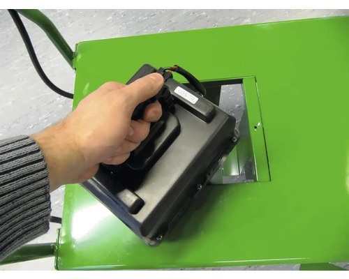 Hand hält Steuergerät an einem grünen Gerät.