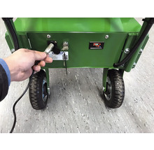 Ein Mann schließt ein Ladegerät an eine grüne Schubkarre mit Batterieanzeige an
