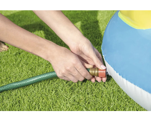 Eine Person füllt mit einem Gartenschlauch einen Pool auf einer Rasenfläche.