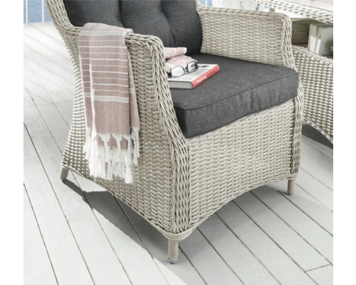 Korbsessel mit grauen Kissen, Buch und Brille