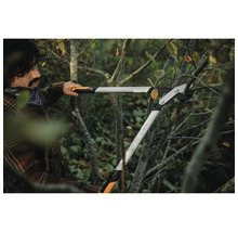 Une personne utilise un ébrancheur à crémaillère pour couper des branches.