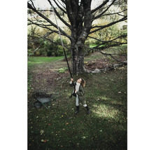 Une femme utilise un sécateur à manche télescopique sous un arbre dans le jardin.