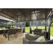 Pavillon vitré avec coin salon et table à manger dans le jardin