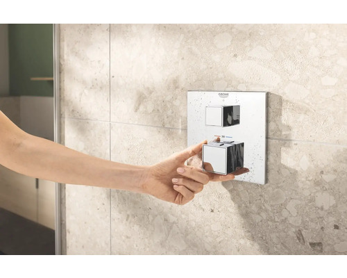 Main actionnant un robinet de douche Grohe