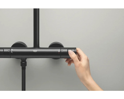 Gros plan d''une main actionnant un mitigeur thermostatique de douche Grohe