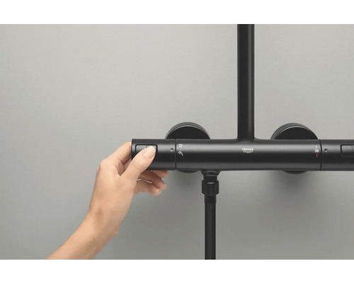 Une main actionne un thermostat de douche Grohe