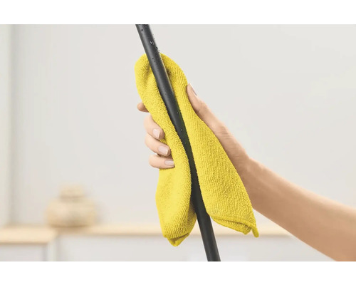 Une main essuie une barre noire avec un chiffon en microfibre jaune
