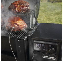 Detailansicht eines Searwood Grills mit Fleisch auf dem Rost und einem Temperaturfühler zur Überwachung des Garzustands.