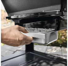 Hand zieht Fettschale eines Grills heraus.