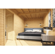 Vue intérieure d'une maison en bois avec lit, table de chevet et porte ouverte