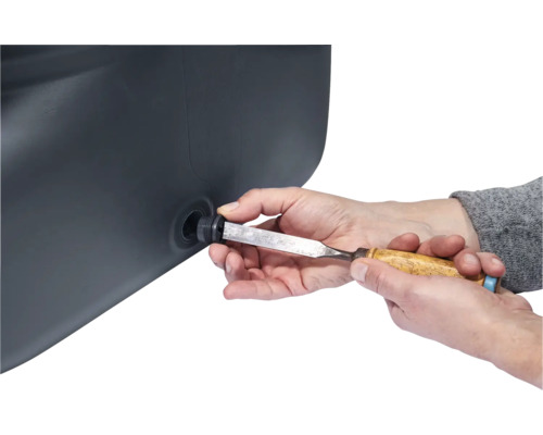 Une personne travaillant sur un récipient noir avec un ciseau