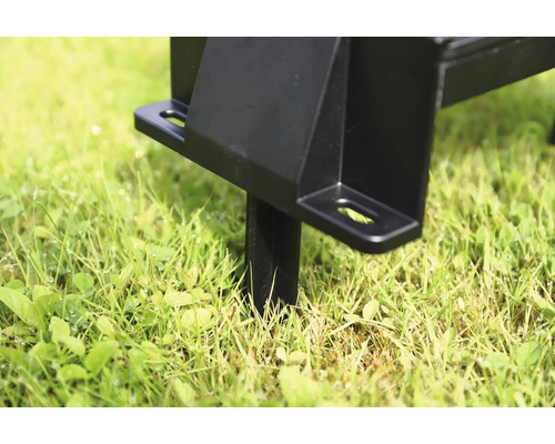 Vue détaillée d''un poteau métallique noir dans l''herbe pour montage dans le jardin