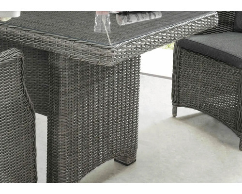 Gros plan d''une table en rotin avec un plateau en verre et une chaise en rotin avec un coussin, idéal pour le jardin