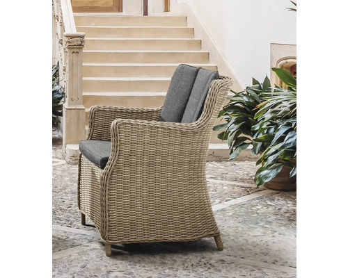 Geflochtener Sessel mit grauen Kissen im Aussenbereich