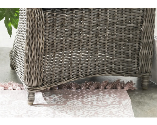 Detailansicht eines Rattansessels mit gemustertem Teppich