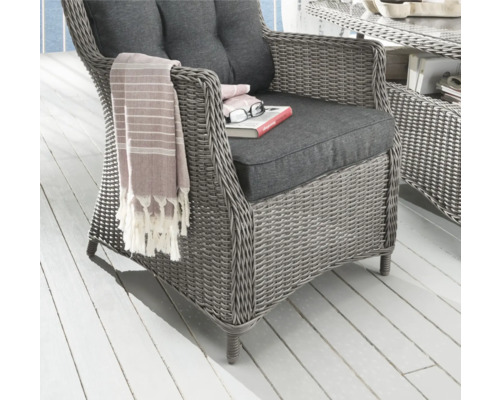 Geflochtener Sessel mit Kissen und Textilien für den Außenbereich