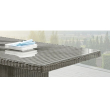 Gros plan d''une table de jardin avec plateau en verre et surface en rotin avec vaisselle