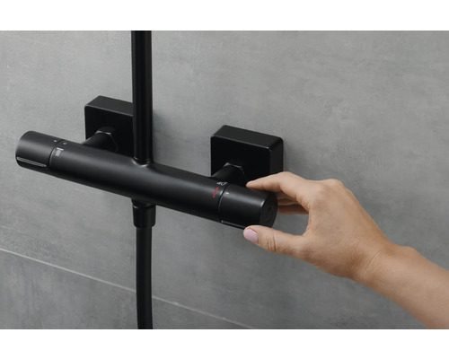 Schwarze Duscharmatur mit Hand beim Einstellen der Temperatur.