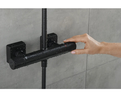 Aufnahme einer Person, die einen schwarzen Duschmischer in einem Badezimmer benutzt.
