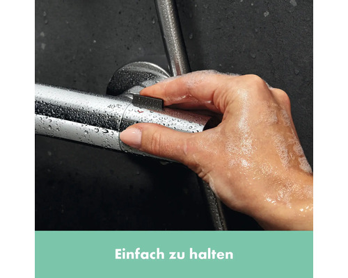 Eine Hand bedient eine Duscharmatur, die mit Wassertropfen bedeckt ist.