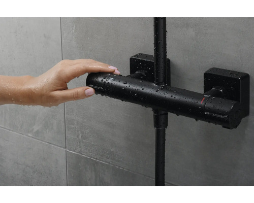 Hand bedient eine schwarze Duscharmatur mit Thermostat