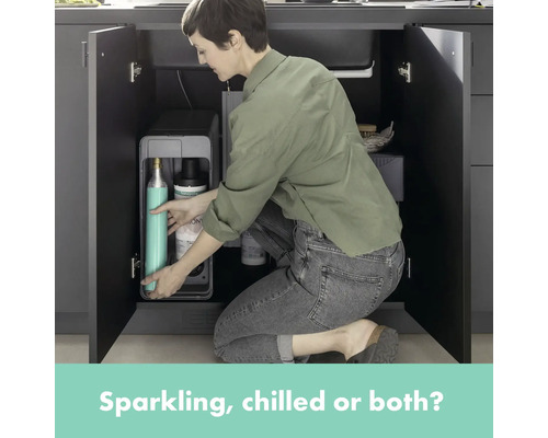 Frau wechselt CO2-Flasche eines Wassersprudlers im Küchenschrank.